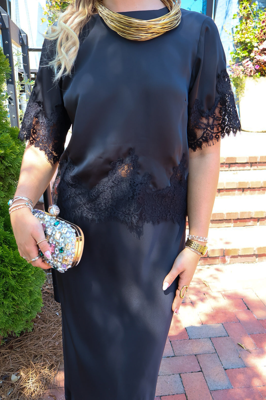 Black satin two-piece set with a lace-trim crop top and matching lace-trim skirt