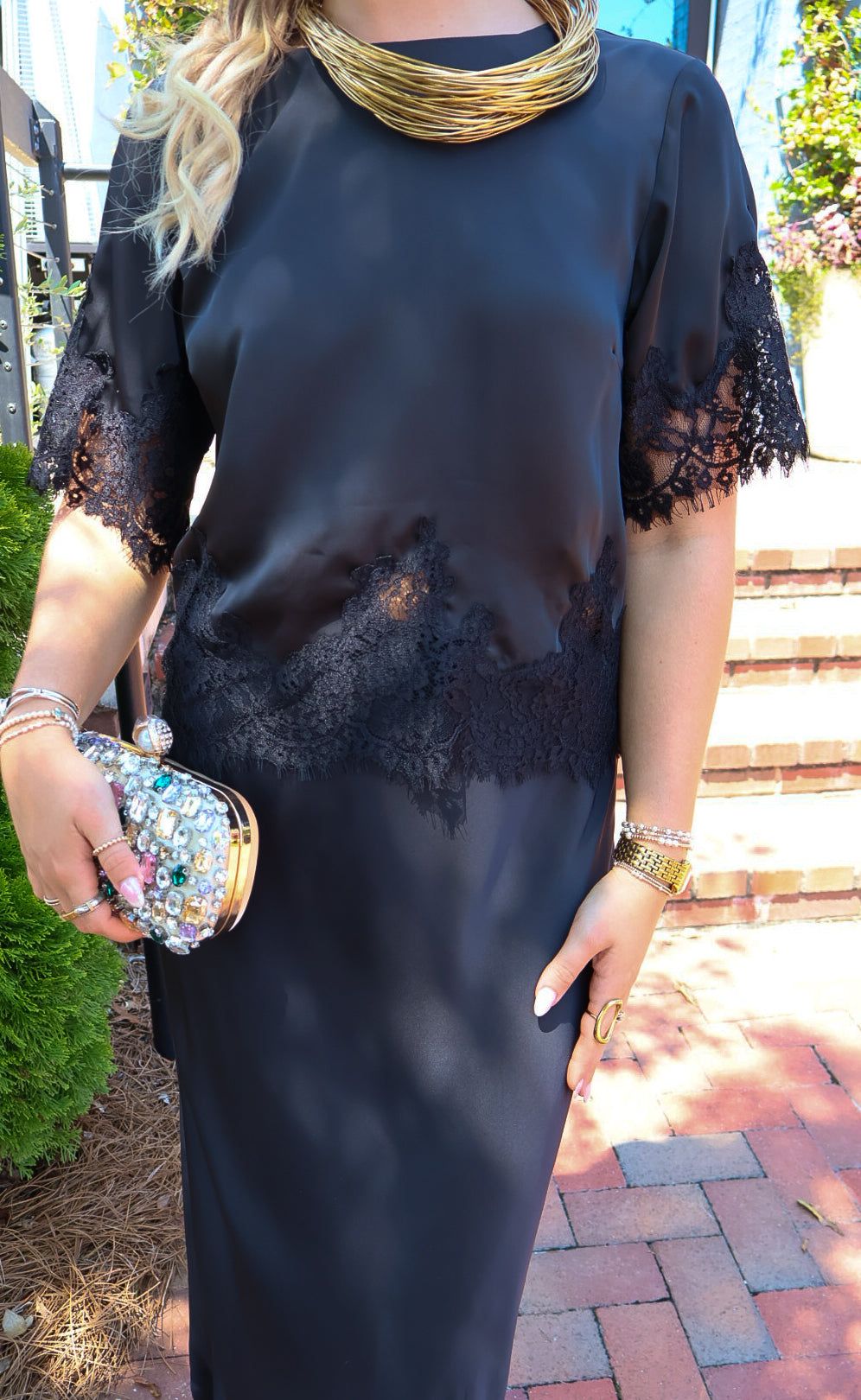 Black satin two-piece set with a lace-trim crop top and matching lace-trim skirt