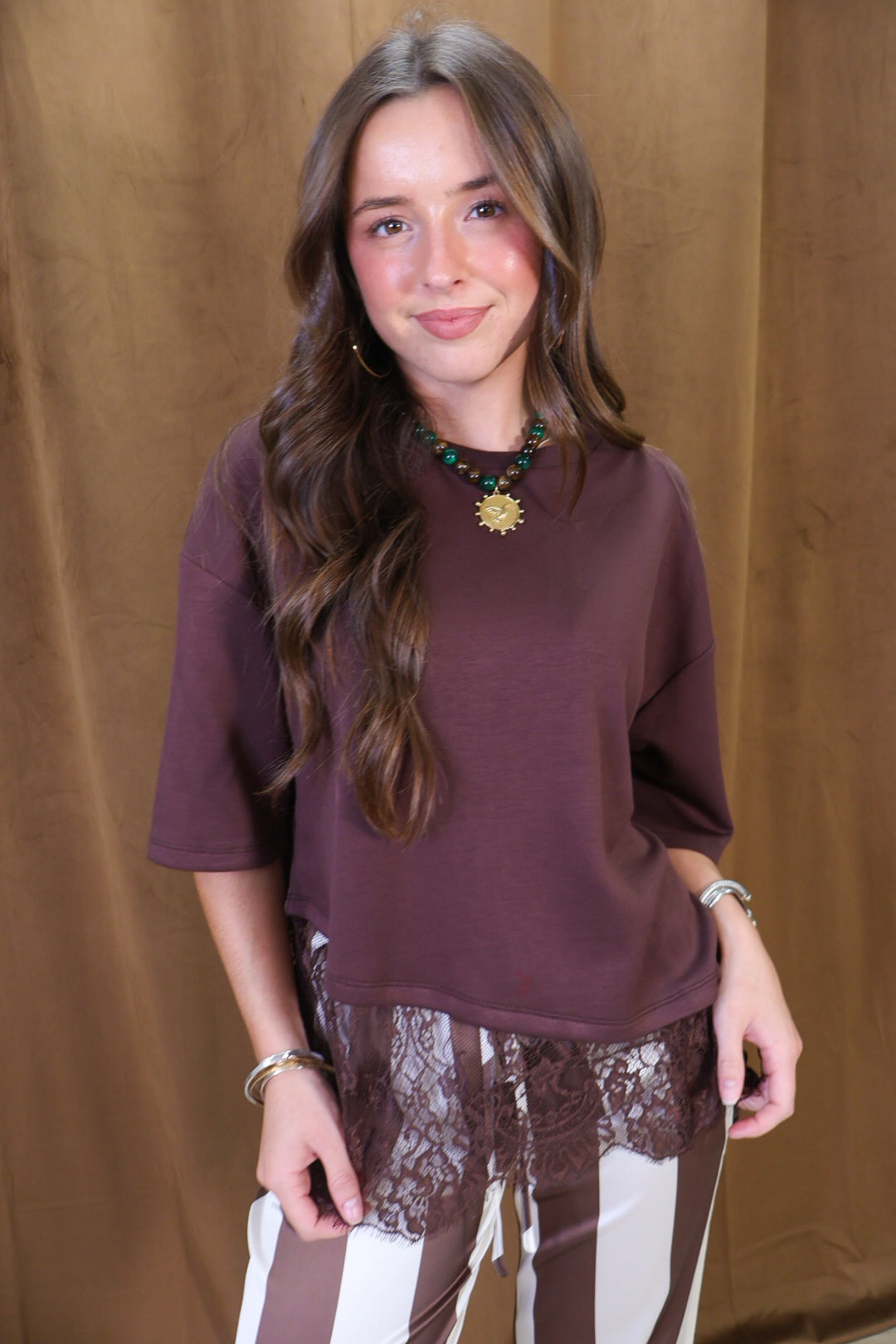 Brown Tee With Asymmetrical Lace Hem — front view with striped pants.