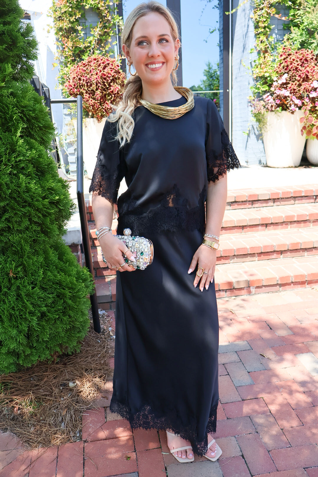 Black satin two-piece set with a lace-trim crop top and matching lace-trim skirt