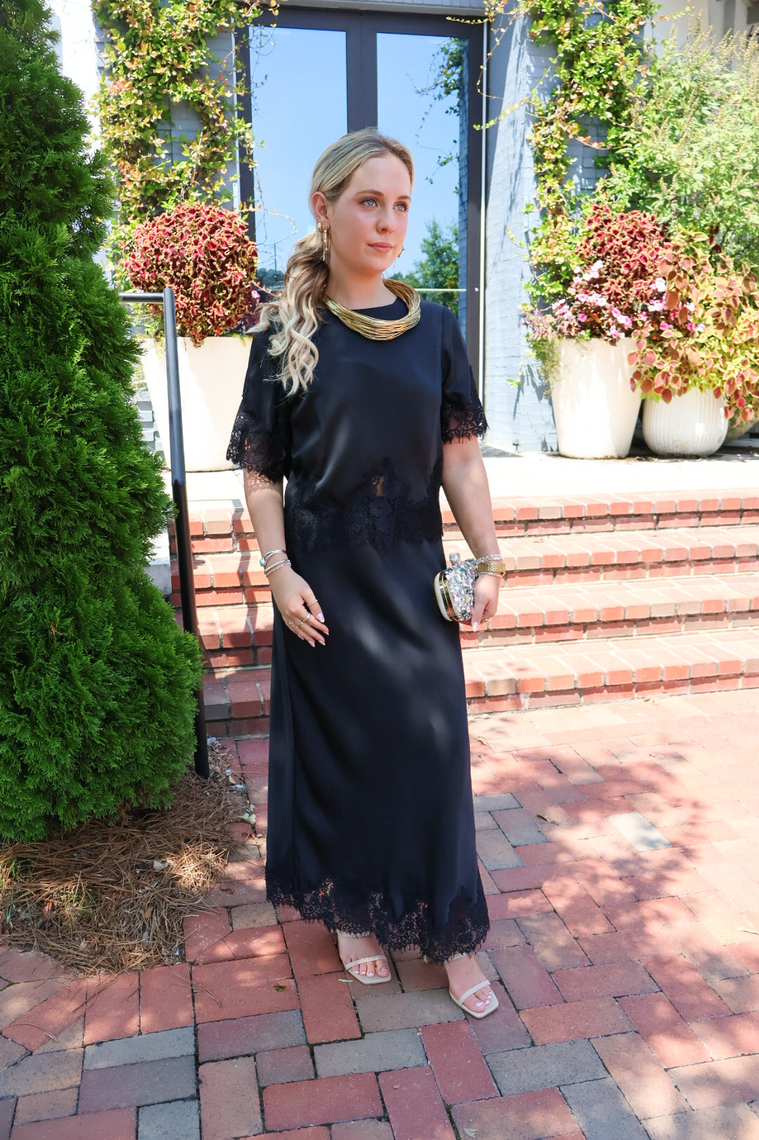 Black satin two-piece set with a lace-trim crop top and matching lace-trim skirt