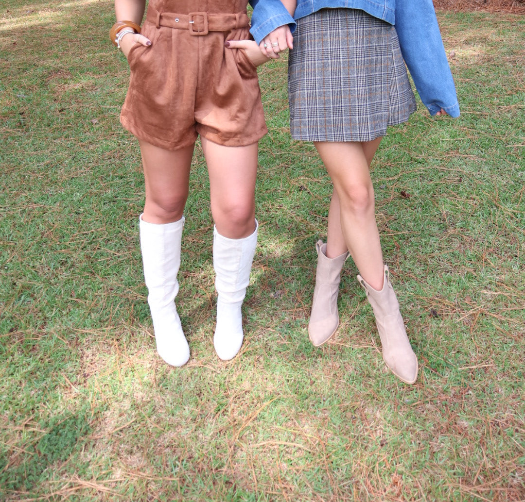 Two women standing outdoors on a grassy area with trees in the background