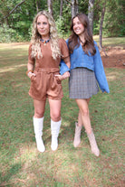 Two women standing outdoors on a grassy area with trees in the background