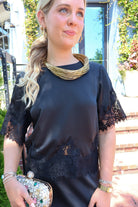 Black satin two-piece set with a lace-trim crop top and matching lace-trim skirt