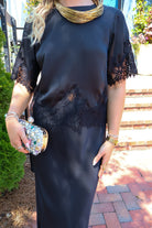 Black satin two-piece set with a lace-trim crop top and matching lace-trim skirt