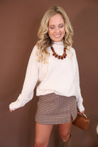Brown Houndstooth Mini Skort — full outfit with tall boots.