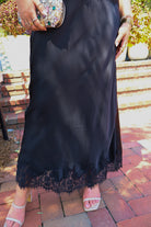 Black satin two-piece set with a lace-trim crop top and matching lace-trim skirt