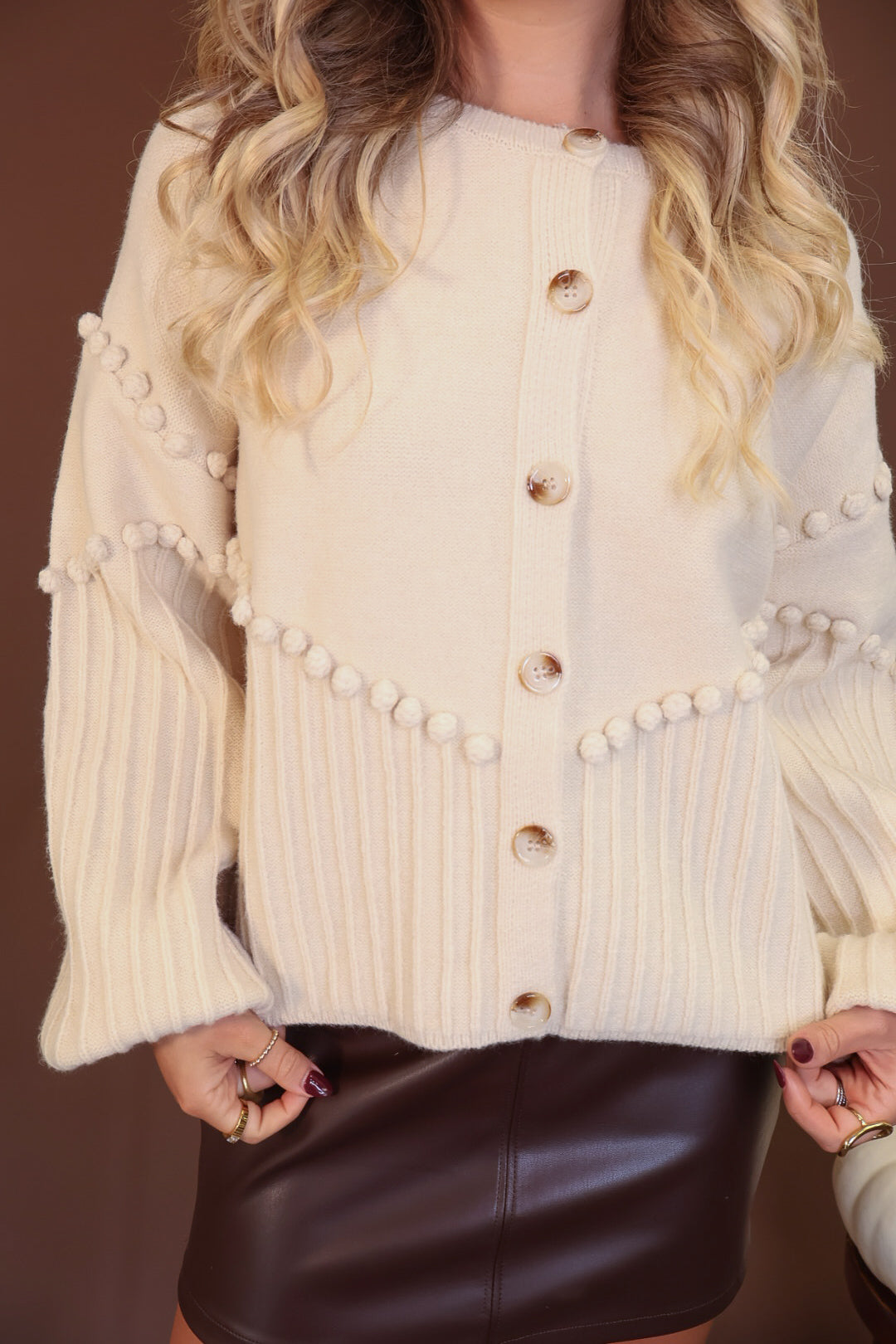 Cream Pom Pom Knit Cardigan — close-up of pom pom details and buttons.