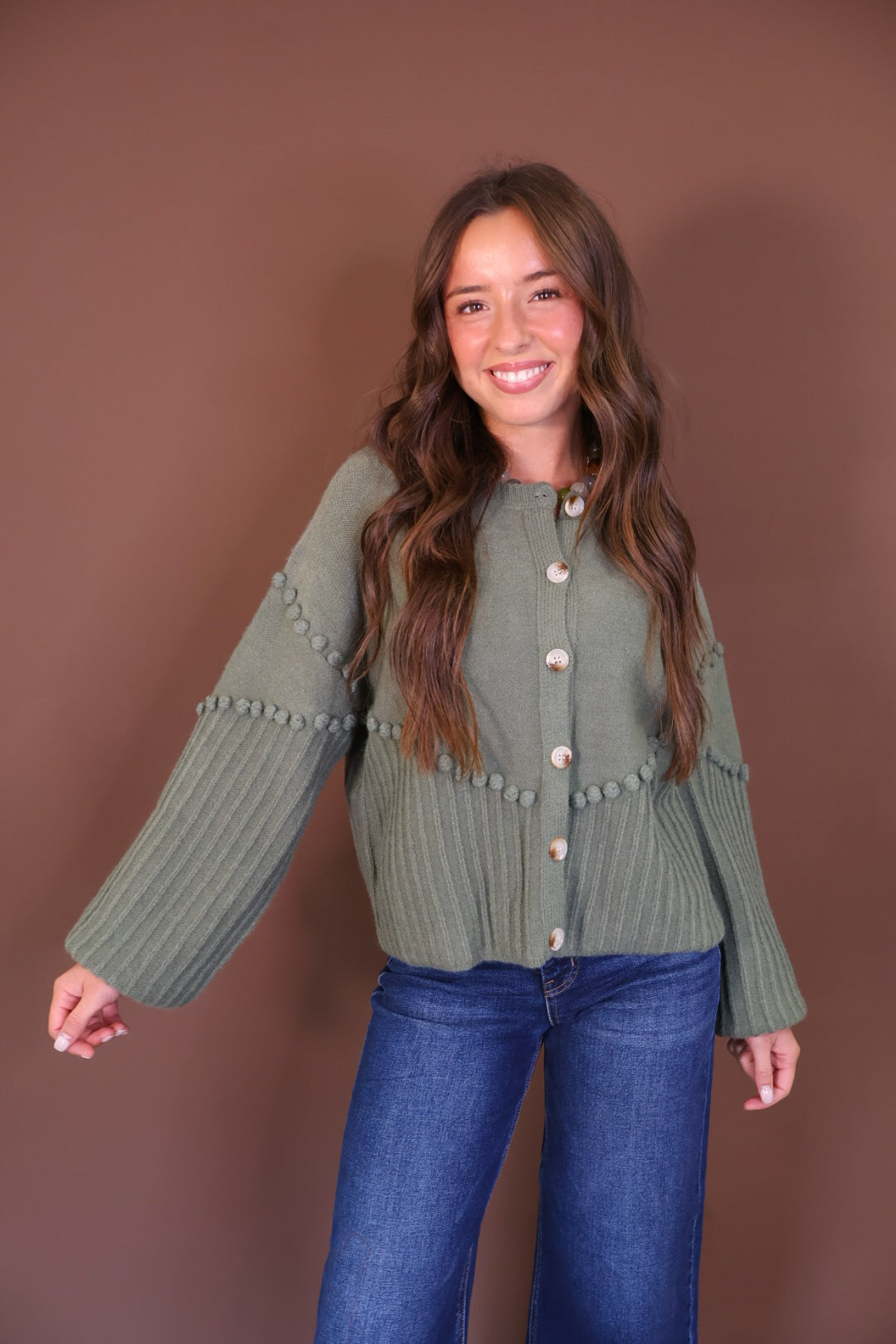 Olive Pom Pom Knit Cardigan — front view with sleeves extended.