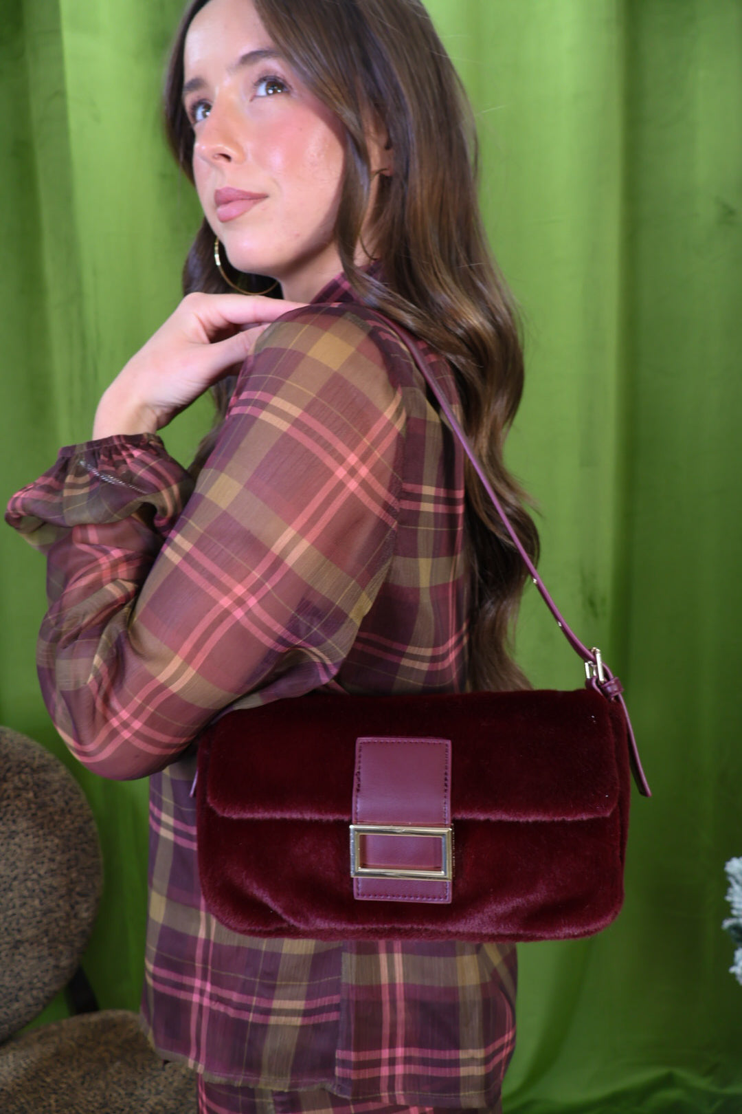 Burgundy plush shoulder bag with rectangular buckle detail.