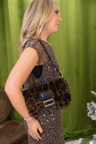 Leopard plush shoulder bag with black trim and gold-tone buckle detail.