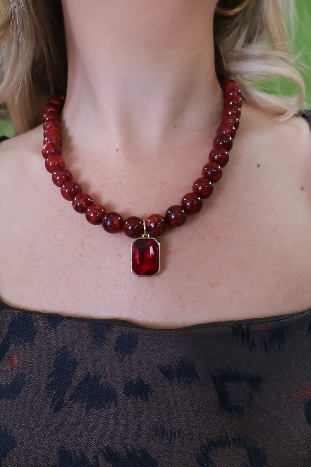 Burgundy beaded necklace with rectangular red pendant.