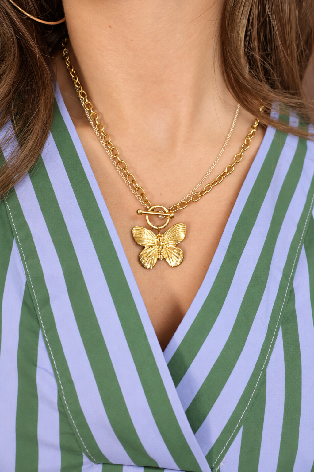 Gold butterfly toggle necklace worn by model