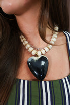 Reversible two-tone heart necklace shown on black side